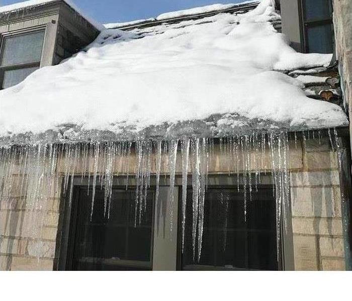 icicle on the roof of a home hanging down in front of a window 